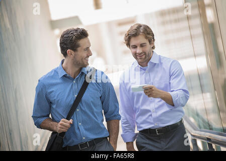 Two businessmen standing in an urban street, using smart phones. Stock Photo