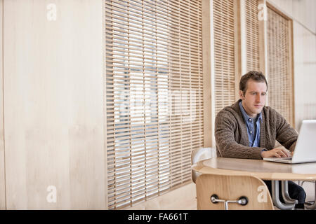 A man sitting at a table on a terrace using a computer laptop. Stock Photo