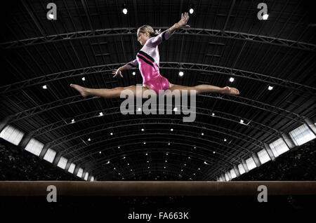 A young woman gymnast performing on the beam, balancing on a narrow piece of apparatus. Stock Photo