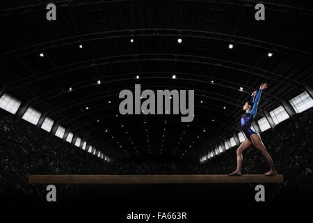 A young woman gymnast performing on the beam, balancing on a narrow piece of apparatus. Stock Photo