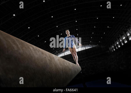 A young woman gymnast performing on the beam, balancing on a narrow piece of apparatus. Stock Photo