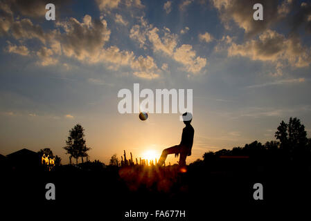 Silhouette of a teenage boy playing football Stock Photo