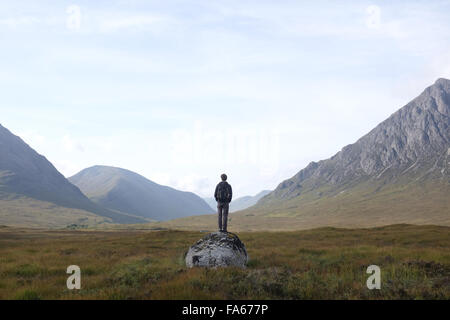 Man standing on a rock looking at mountain landscape, Highlands, Scotland, United Kingdom Stock Photo