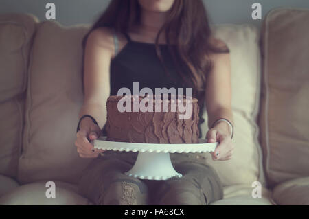 Girl holding chocolate cake on a cake stand Stock Photo