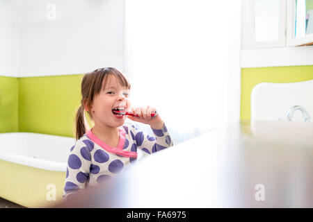 Girl brushing teeth in bathroom Stock Photo