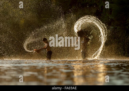 Silhouette of two boys playing in river, Thailand Stock Photo