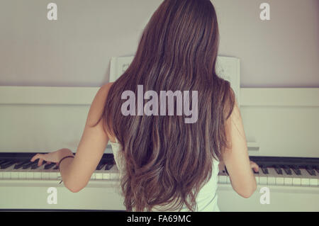 Rear view of girl playing the piano Stock Photo