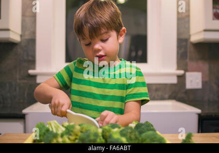 Boy in kitchen chopping broccoli Stock Photo