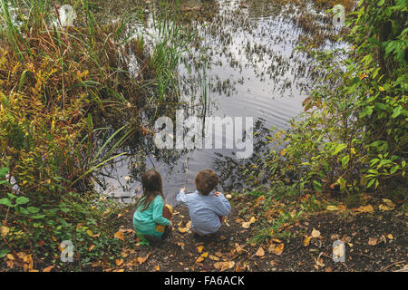 Elevated view of boy and girl sitting by a lake Stock Photo