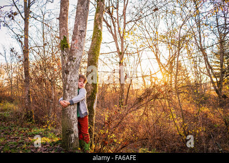 Boy hugging a tree in the forest