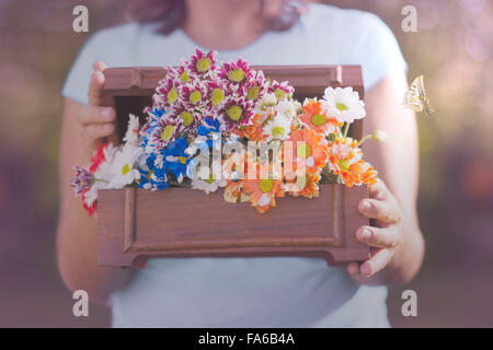 Butterfly flying next to a woman holding box of flowers Stock Photo