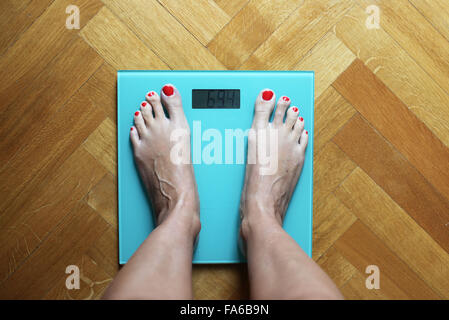 Woman standing on weighing scales Stock Photo