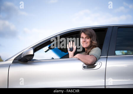 Teenage girl sitting in a car holding up  keys to new car Stock Photo