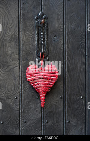 Red Christmas love heart decoration on a wooden door. Cotswolds, England Stock Photo