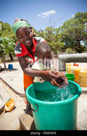 A mother and child draw clean water from a borehole in Mecupes village, Northern Mozambique. Stock Photo