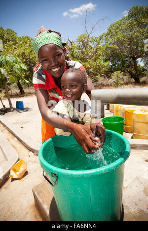 A mother and child draw clean water from a borehole in Mecupes village, Northern Mozambique. Stock Photo