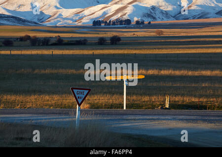 Omakau - Ranfurly road sign on State Highway 85, and Ida Range in winter, Hills Creek, Maniototo, Central Otago, New Zealand Stock Photo