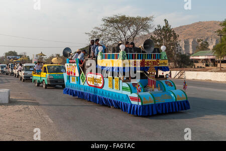 Extensively decorated truck carrying many people and loudspeakers during a festive procession in central Myanmar. Stock Photo