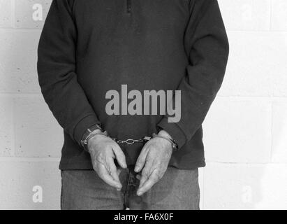Mature man in handcuffs, focus is on his hands. Stock Photo