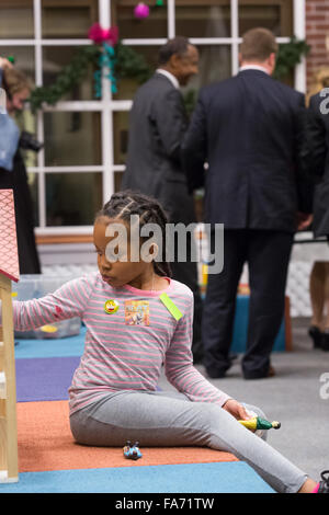 Charleston, South Carolina, USA. 22nd Dec, 2015. A young patient plays with her dolls unaware of retired Neurosurgeon and Republican presidential candidate Dr. Ben Carson in the background during a visit to the MUSC Children's Hospital December 22, 2015 in Charleston, South Carolina. Carson stopped by to listen to Christmas carols and greet the young patients. Stock Photo