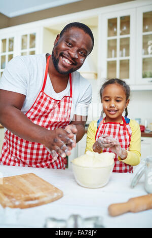 Happy young man and little girl making pastry from dough Stock Photo