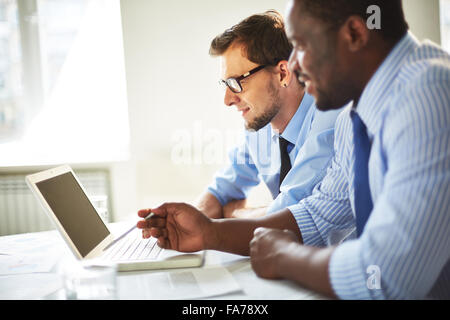 Two businessmen working with laptop together at the table Stock Photo