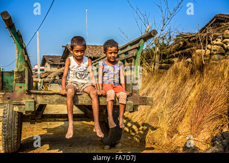 Two nepalese boys sitting on a wooden cart Stock Photo