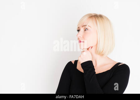 Decision making - difficult life choices and options : A young slim blonde blond haired woman girl, thinking, pondering, thoughtful, UK Stock Photo