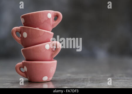 Little pink toy porcelain cups with white dots on gray background Stock Photo