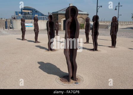Assembly, by Peter Burke, Woolwich Arsenal, London. Statues standing in a group in an open space. Modern architecture of the Olympic park. Stock Photo