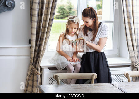 Caring mother teaching cute daughter how to read Stock Photo