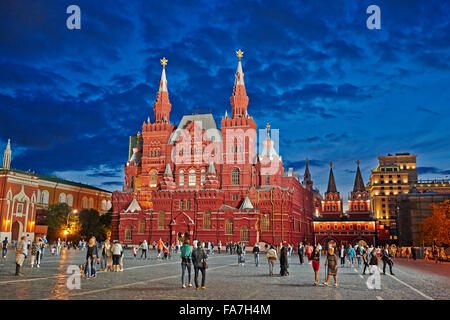 People walking on the Red Square in front of the State Historical Museum illuminated at dusk. Moscow, Russia. Stock Photo
