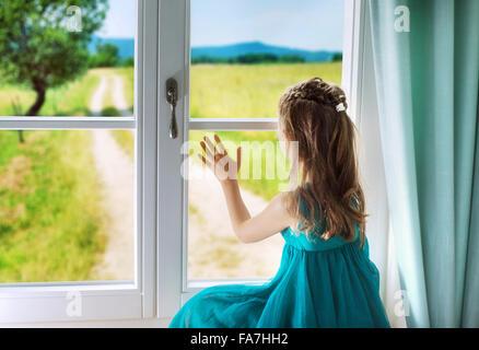 Little sad girl looking through window Stock Photo
