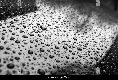 Black shining metallic car hood with raindrops, photo with selective focus and shallow DOF Stock Photo