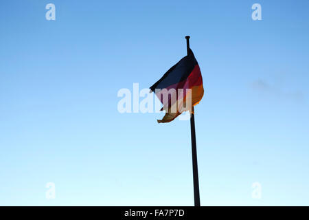 A German flag flies on the Reichstag Building in Berlin, Germany. The tricolour is coloured black, red and gold. Stock Photo