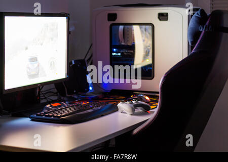 Custom built desktop computer for gaming on the table with joystick, monitor, keyboard, chair under low light. Selective focus. Stock Photo