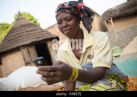 A farmer uses mobile phone technology to compare prices at various markets within Banfora Department, Burkina Faso, West Africa. Stock Photo