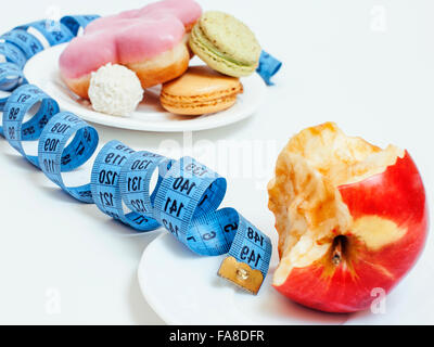 new diet concept, question sign in shape of measurment tape between red apple and donut isolated on white Stock Photo