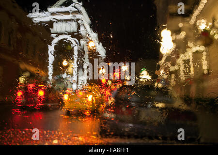 Raindrops on car windshield with building and car taillights in background at night-Victoria, British Columbia, Canada. Stock Photo