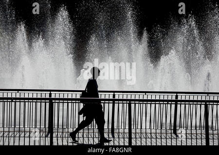 A man walks through Piccadilly gardens in Manchester in the early morning sun .  www.chris Stock Photo