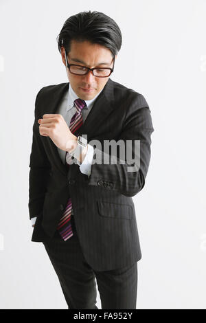 Studio Shot Of Mature Asian Businessman Holding Clipboard Against Gray 