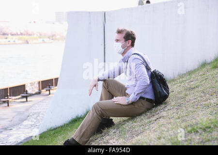 Caucasian male wearing a mask sitting on lawn Stock Photo