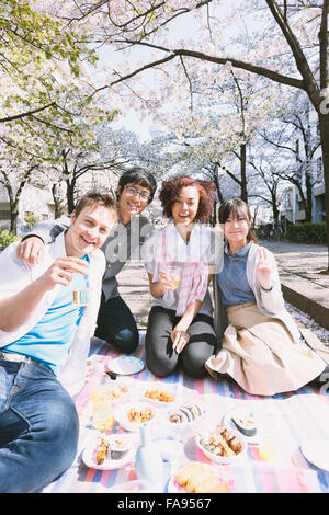 Multi-ethnic group of friends enjoying cherry blossoms blooming in Tokyo Stock Photo