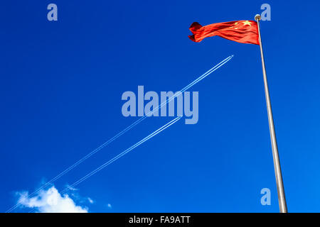 The national flag of China. A long trail of jet plane on blue sky. Stock Photo