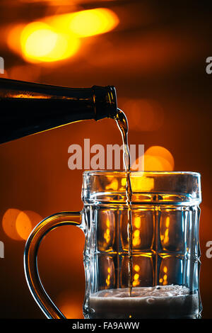 dark beer is  poured into a glass mug from a bottle Stock Photo