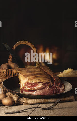 smoked pork chop with Sourcrout and Potatoes on a wooden Table before a Fireplace Stock Photo