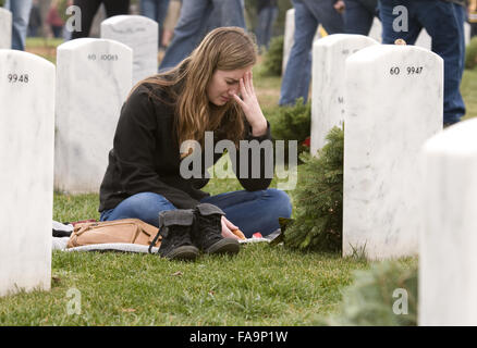 Emily Johnson pauses at the grave of her older brother, Army 1st Lt. David Andrew Johnson, killed by an improvised explosive device in 2012 during Wreaths Across America in Arlington National Cemetery December 12, 2015 in Arlington, Virginia. Hundreds of thousands wreaths are placed at the graves of fallen service members by volunteers and family members during the event. Stock Photo