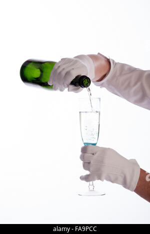 Waitress wearing white cotton gloves pouring sparkling wine from a green bottle Stock Photo