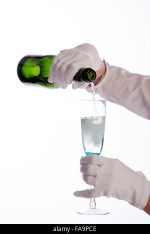 Waitress wearing white cotton gloves pouring sparkling wine from a green bottle Stock Photo