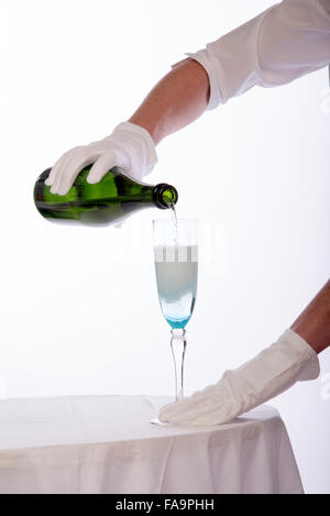 Waitress wearing white cotton gloves pouring sparkling wine from a green bottle Stock Photo